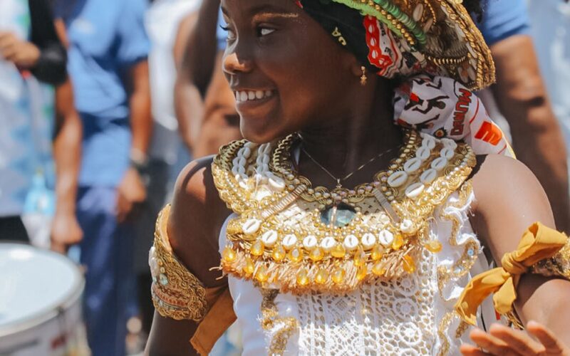 A young girl in traditional attire celebrates amidst a lively street festival in Salvador, Bahia, Brazil.