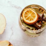 cravo-da-índia com limão — Flat lay of herbal tea with apple slices, dried lemon, and star anise on marble.
