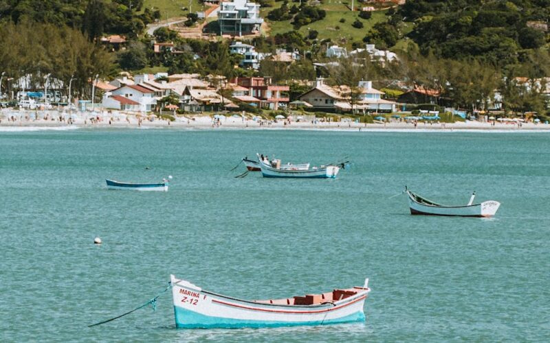 destinos subestimados no Brasil — Idyllic view of boats floating on Garopaba Bay with lush hillside backdrop in Brazil.