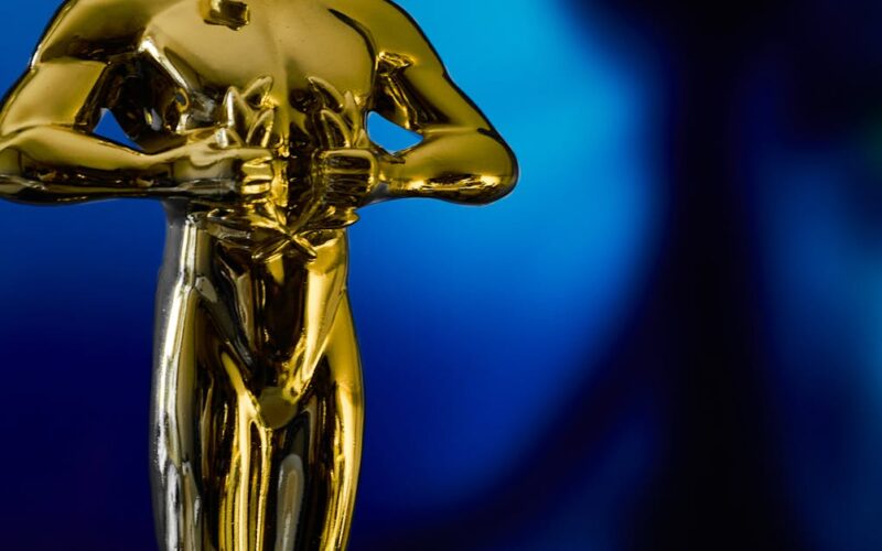 Oscar 2026 — A shining Oscar statuette, symbolizing achievement in the film industry, against a vibrant blue backdrop.