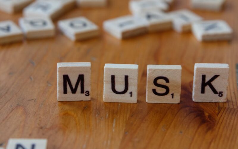 ranking bilionários Elon Musk — Close-up of Scrabble tiles spelling 'MUSK' on a wooden table, ideal for business and innovation themes.