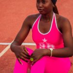 preparo emocional e físico no esporte — Young female athlete in pink sportswear sitting on a running track during the day.