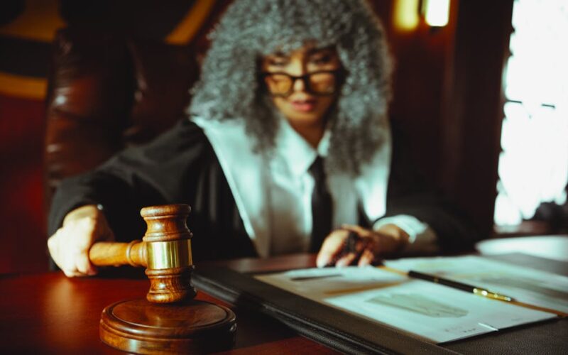 funcionamento do sistema judiciário — Female judge in a courtroom setting, focusing on legal documents with a gavel.