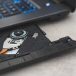 golpes CNH Social — Modern laptop showing open CD drive, highlighting optical disk technology.