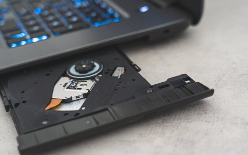 golpes CNH Social — Modern laptop showing open CD drive, highlighting optical disk technology.