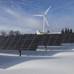 transição energética no Brasil — Solar panels and wind turbine in a snowy landscape, showcasing renewable energy sources.