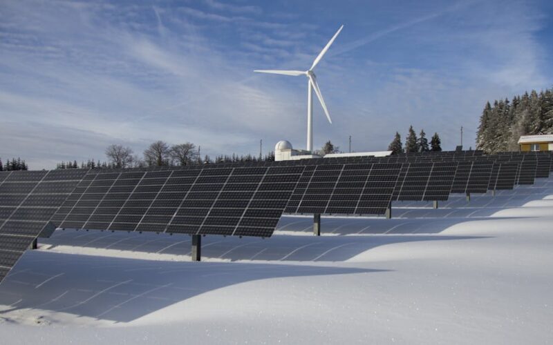transição energética no Brasil — Solar panels and wind turbine in a snowy landscape, showcasing renewable energy sources.