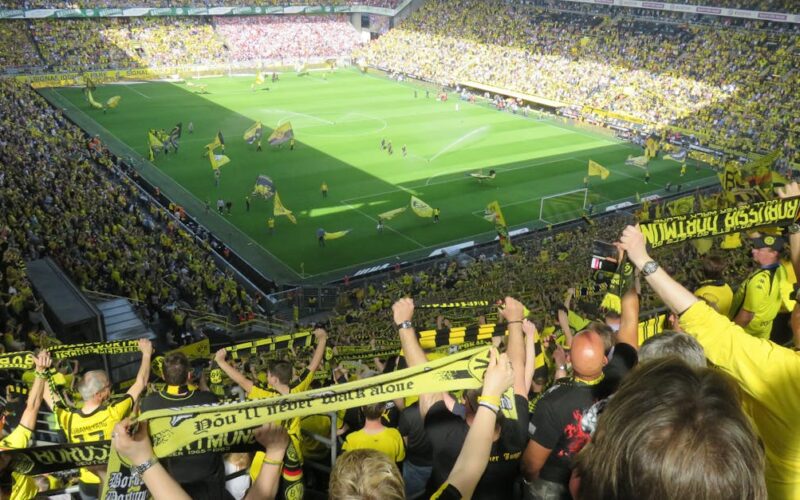Série B Brasileiro 2026 — Excited Borussia Dortmund fans cheering during an intense soccer match at the stadium.