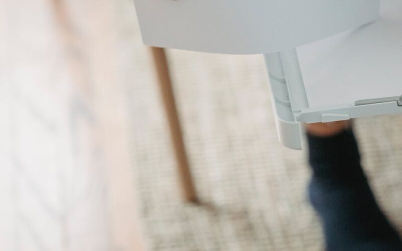 organizar documentos pessoais — From above of crop anonymous female remote worker sitting on chair and preparing paper for printing document