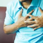 sinais e prevenção do AVC — A close-up image of a man clutching his chest, indicating heart pain or discomfort.