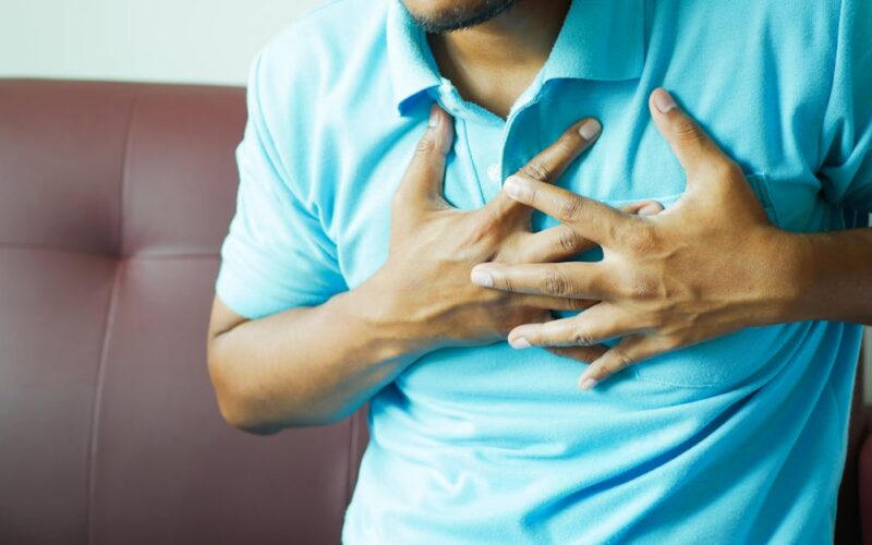 sinais e prevenção do AVC — A close-up image of a man clutching his chest, indicating heart pain or discomfort.