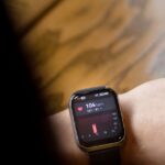 tecnologia vestível saúde desempenho — A close-up shot of a smartwatch on a wrist showing a heart rate of 104 bpm.