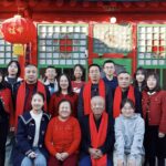 significado da Páscoa — A large family poses in front of a Chinese architectural backdrop with red decorations.