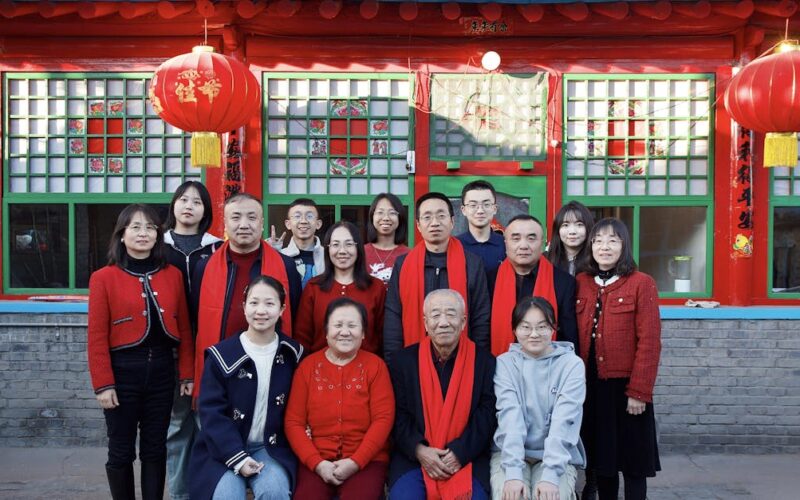significado da Páscoa — A large family poses in front of a Chinese architectural backdrop with red decorations.
