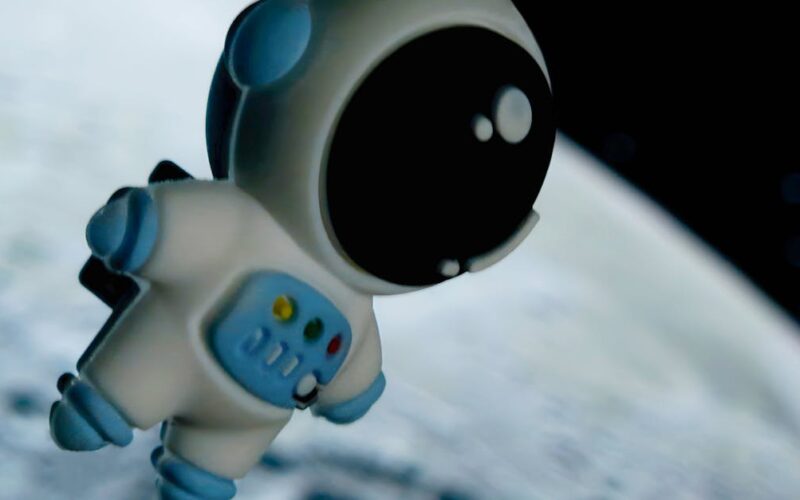 missão Artemis 2 — Adorable toy astronaut floating against a moonlit space background, capturing a sense of wonder.
