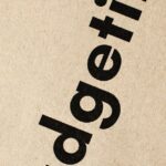 planejamento financeiro aposentadoria — Detailed close-up of the word 'Budgeting' printed on brown textured paper.