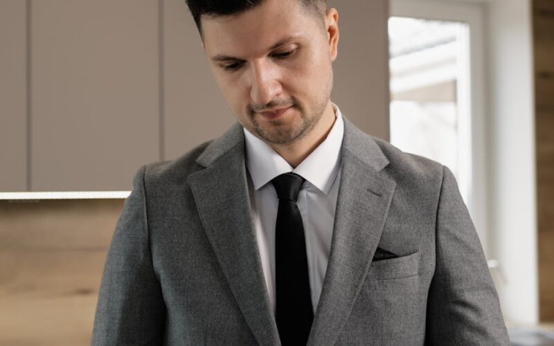 venda parcelada imóvel IR — Male real estate agent in suit reviewing property documents indoors.