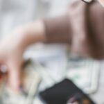usar FGTS para quitar dívidas — A woman calculates finances using a calculator with banknotes and documents on the table.