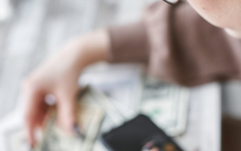 usar FGTS para quitar dívidas — A woman calculates finances using a calculator with banknotes and documents on the table.