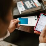 PIX fora do ar — Person making an online payment using a smartphone and credit card indoors.