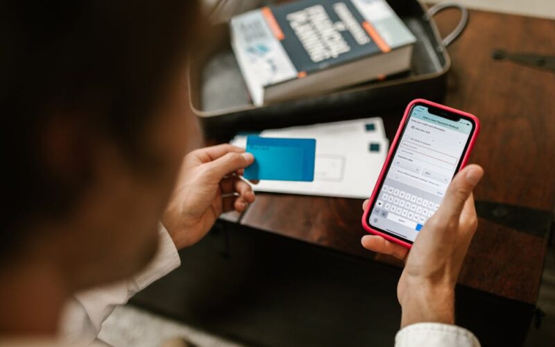 PIX fora do ar — Person making an online payment using a smartphone and credit card indoors.