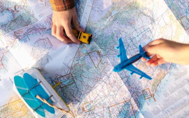 planejar viagem feriadão — Hands holding a toy airplane and car over a map, symbolizing travel planning and exploration.