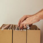 Organizar documentos pessoais — Close-up of a person organizing files in cardboard boxes, ideal for business and office themes.