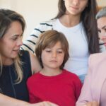 ressarcimento INSS feminicídio — A family of four discussing real estate documents indoors with their realtor.
