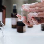 prevenir infecções por superbactérias — Close-up of hands washing with soap by a running faucet in a stylish bathroom.