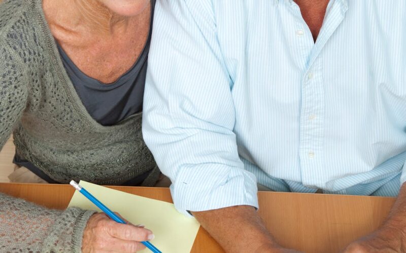 planejamento financeiro melhor idade — Happy senior couple using a laptop and calculator for financial planning.