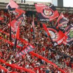 Uniformes históricos do Flamengo 2027 — A lively crowd of Flamengo supporters waving flags at Maracanã Stadium in Rio de Janeiro.
