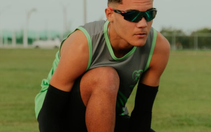 Seleção brasileira atletismo Sub-20 — Focused young athlete tying shoelaces on track, ready for training in Rio de Janeiro.