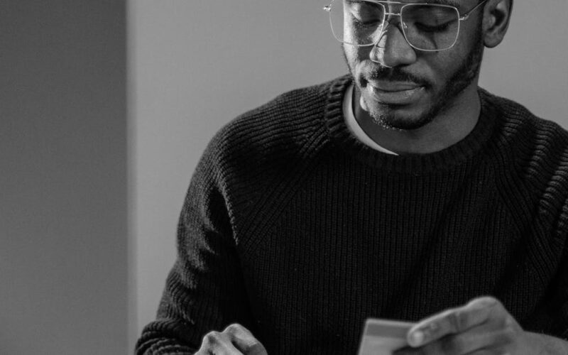 fraudes em cartões de benefício — A man intensely reviews financial data and card details, indicating cybersecurity awareness.
