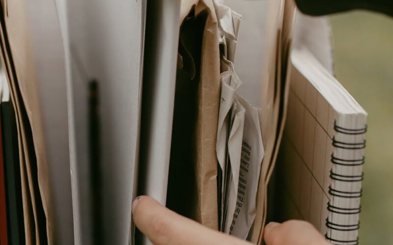 organizar e proteger documentos pessoais — Hands arranging papers and notebooks in a box, highlighting organization and office work.
