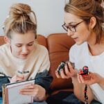 feriados prolongados viagens curtas — A mother and daughter planning a trip with a map and notebook in a cozy living room.