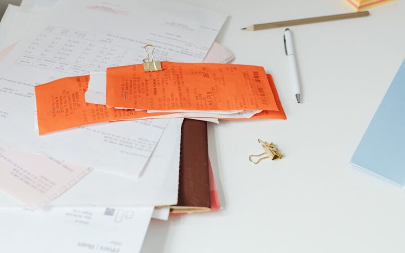 organizar documentos pessoais — Close-up of a tidy desk with receipts, documents, and office stationery for business organization.
