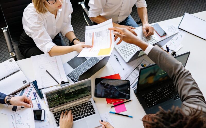 feriado dia do trabalho pagamento quinto dia útil — Diverse team collaborating in a modern office with laptops and documents.