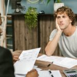 Renegociação de dívidas Desenrola 2.0 — Man in office, appearing stressed during paperwork discussion, sitting opposite professional.
