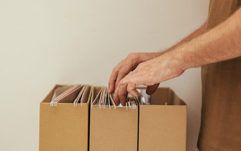 organizar documentos pessoais — Close-up of a person organizing files in cardboard boxes, ideal for business and office themes.