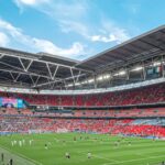 assistir jogos de futebol ao vivo — Vibrant crowd enjoys a soccer match at a bustling stadium under a clear sky.