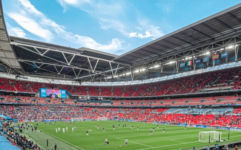 assistir jogos de futebol ao vivo — Vibrant crowd enjoys a soccer match at a bustling stadium under a clear sky.