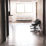 filas cirurgias ortopédicas público — A dimly lit empty corridor with chairs and a waiting area, conveying a quiet atmosphere.