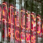 grunge anos 1990 — Colorful neon sign of a record shop with urban street art in background.