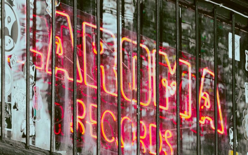 grunge anos 1990 — Colorful neon sign of a record shop with urban street art in background.