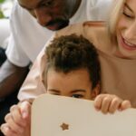 família de acolhimento — Interracial family enjoying quality time reading a book indoors together.