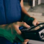 tecnologia Harness — Close-up of technician using a handheld control device in a manufacturing setting.