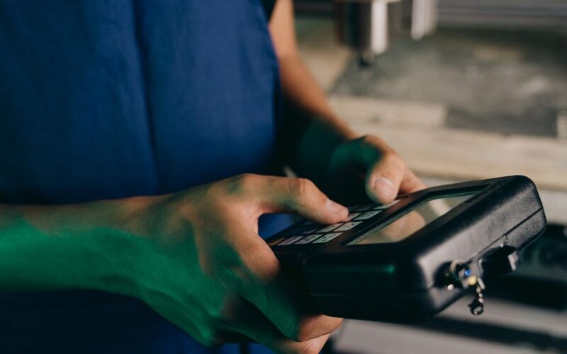 tecnologia Harness — Close-up of technician using a handheld control device in a manufacturing setting.