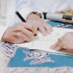 planejar testamento — Close-up of hands signing wedding documents with microphone on table.