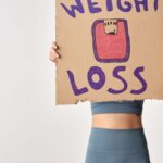 golpes com produtos emagrecedores — Person holding 'weight loss' sign for fitness motivation and health goals.