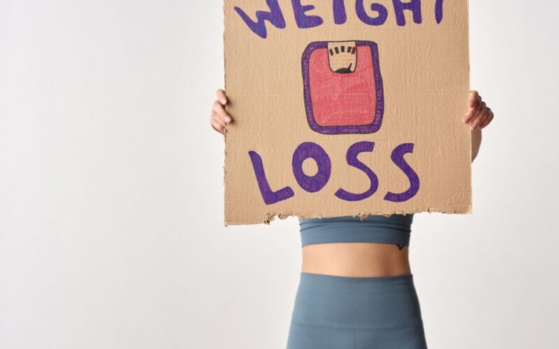 golpes com produtos emagrecedores — Person holding 'weight loss' sign for fitness motivation and health goals.